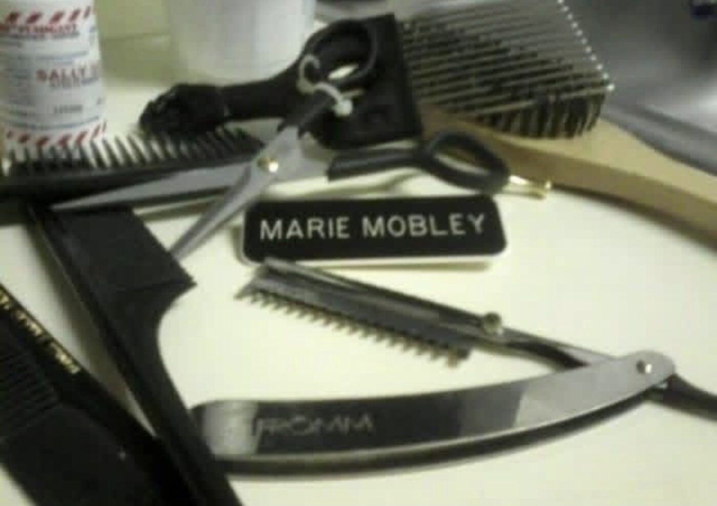 Marie Mobley's shears, razor, and nameplate laid out at her station